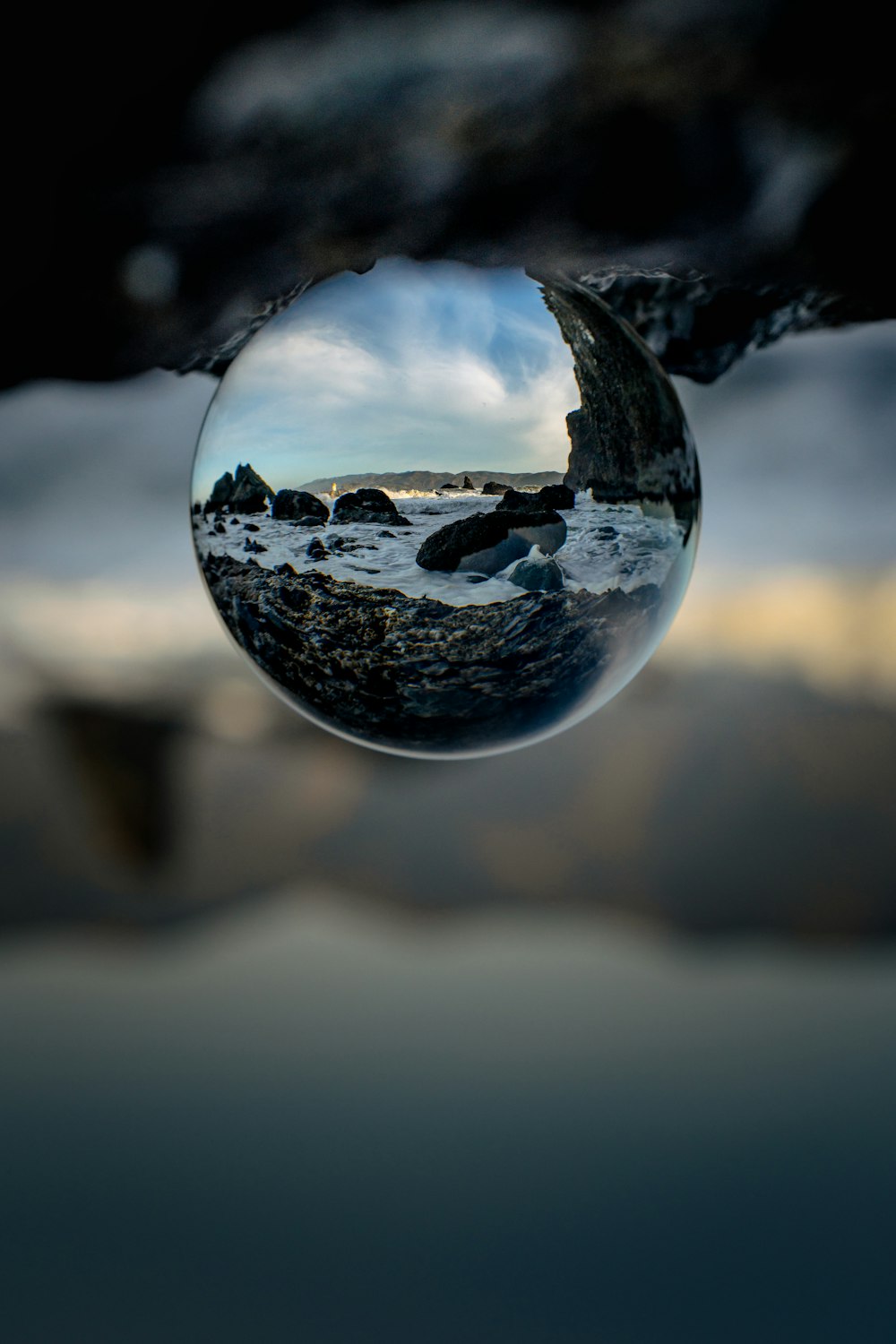 a reflection of a rocky beach in a water drop