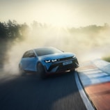 A spirited drift car sliding through a corner, smoke billowing from its tires against a sunset backdrop.