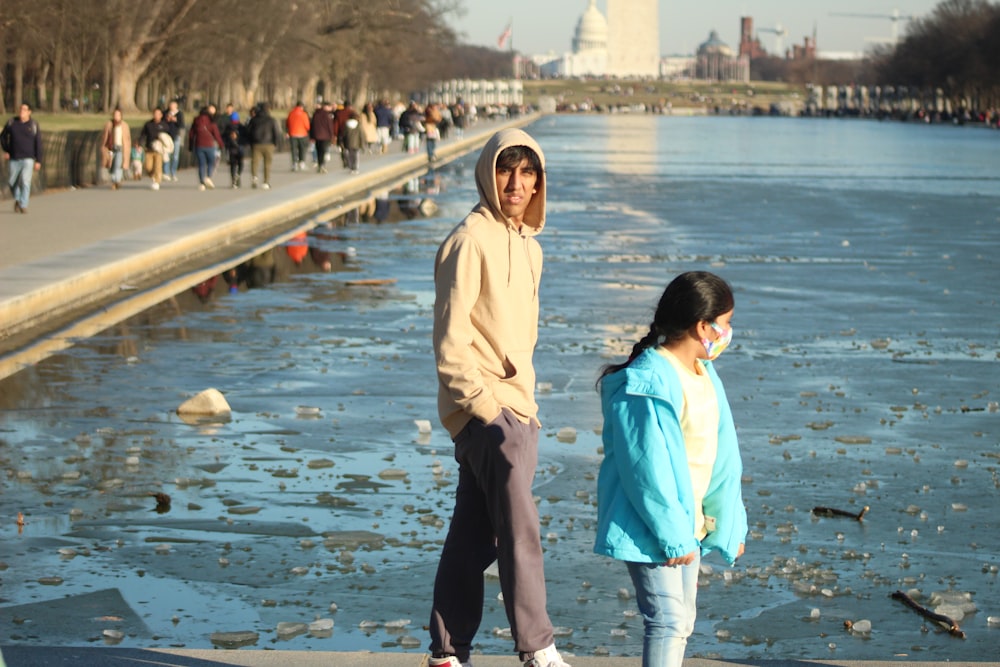 a couple of people standing next to a body of water