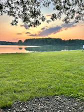 A serene view of the private lake at l'oasis during sunset, with lush greenery surrounding the water.