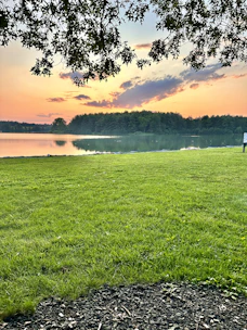 A serene view of the private lake at l'oasis during sunset, with lush greenery surrounding the water.