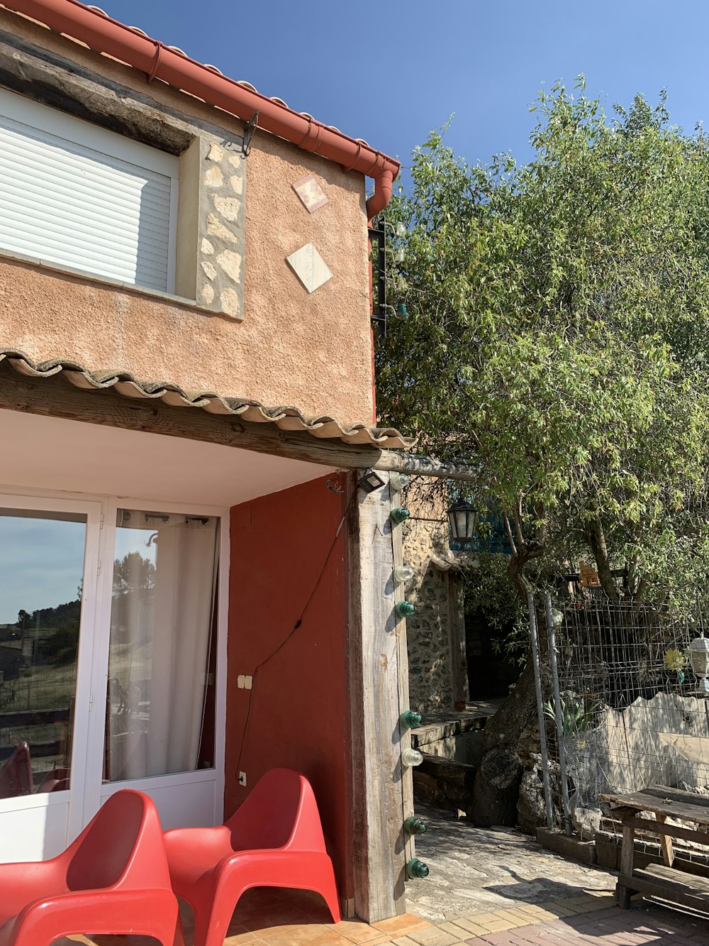 a red chair sitting outside of a house next to a tree