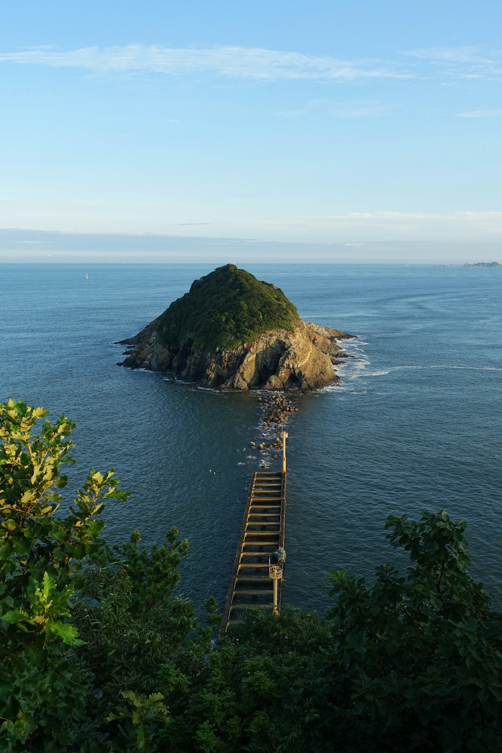 a wooden walkway leading to a small island in the middle of the ocean