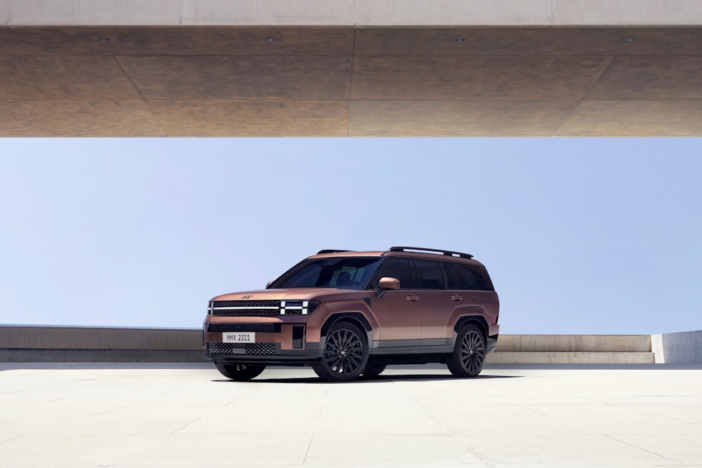 a brown suv is parked under a bridge