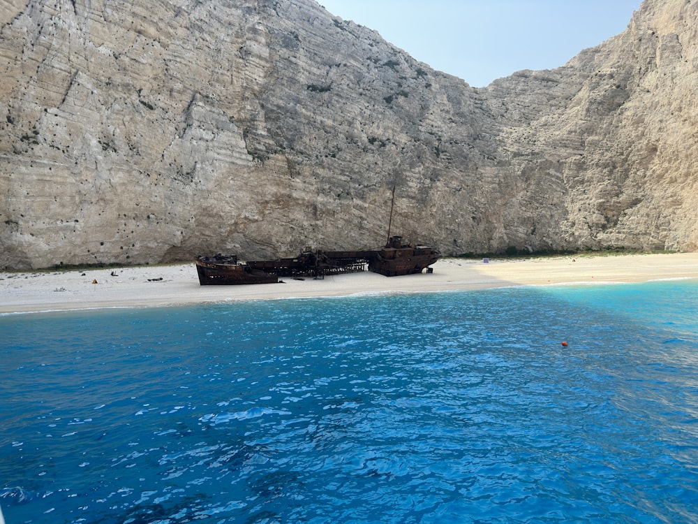 a boat sitting on top of a beach next to a mountain