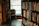 A warm, inviting reading nook with a soft cream armchair and a stack of books beside a window.