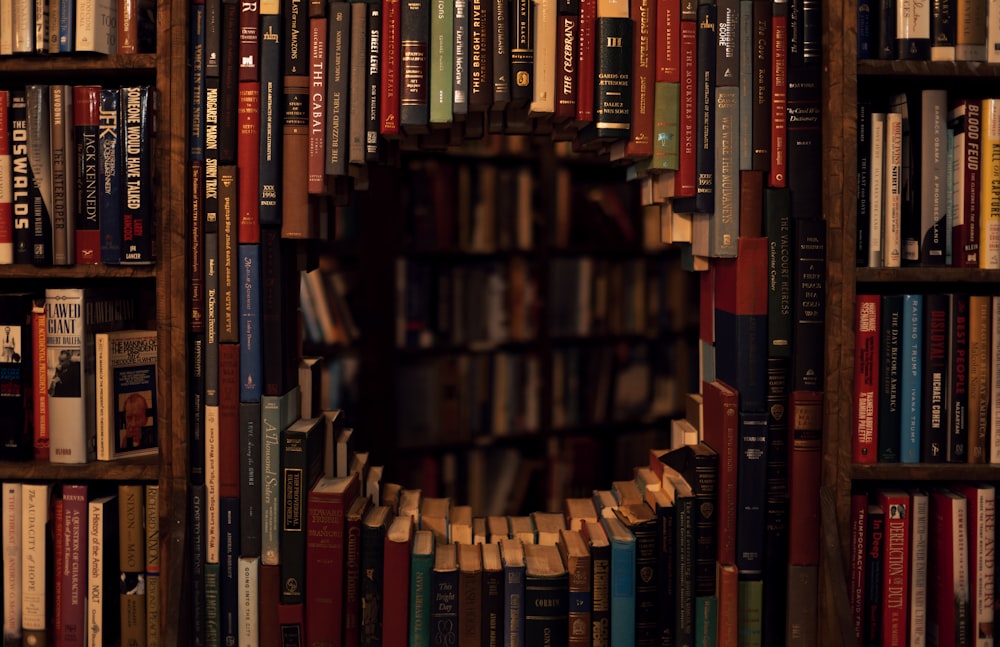 a bookshelf filled with lots of books next to a clock