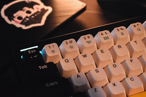 A close-up of hands typing on a mechanical keyboard with cybersecurity stickers.