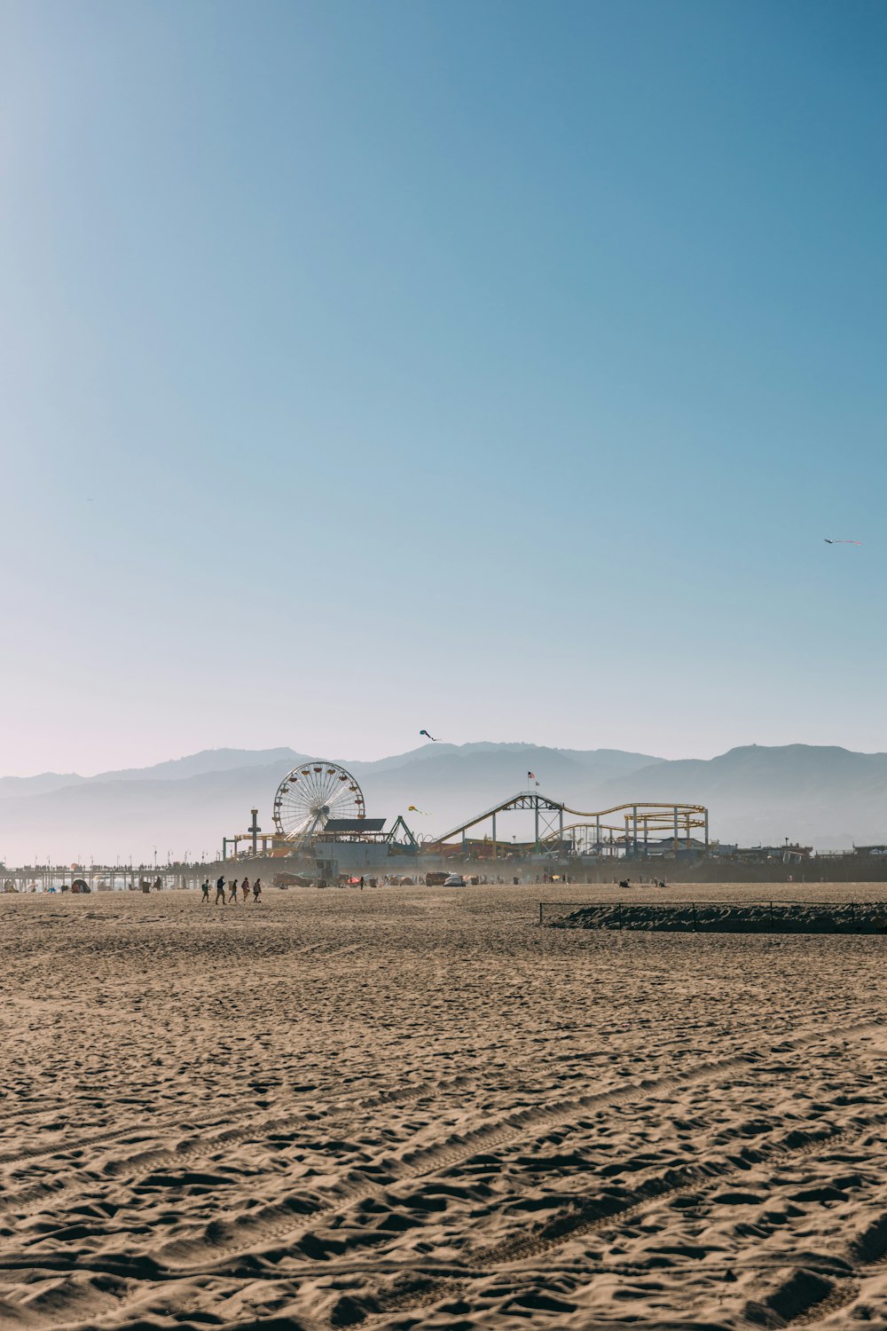 a sandy beach with a ferris wheel in the distance