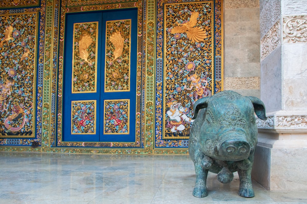 a statue of a pig in front of a blue door