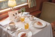 A carefully arranged breakfast table with pastries, coffee, and fresh flowers in a bright kitchen.
