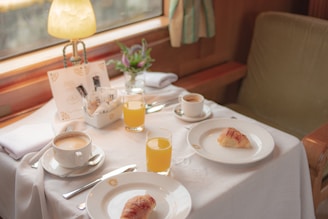 A cozy restaurant table set with a fresh breakfast plate, a cup of coffee, and a glass of natural juice.