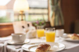 A cozy breakfast scene with a cup of coffee, croissants, and fresh orange juice on a bright morning.