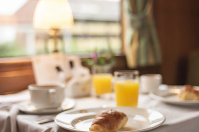 A cozy breakfast scene with a cup of coffee, croissants, and fresh orange juice on a bright morning.