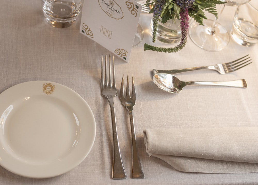 a table set for a formal dinner with silverware