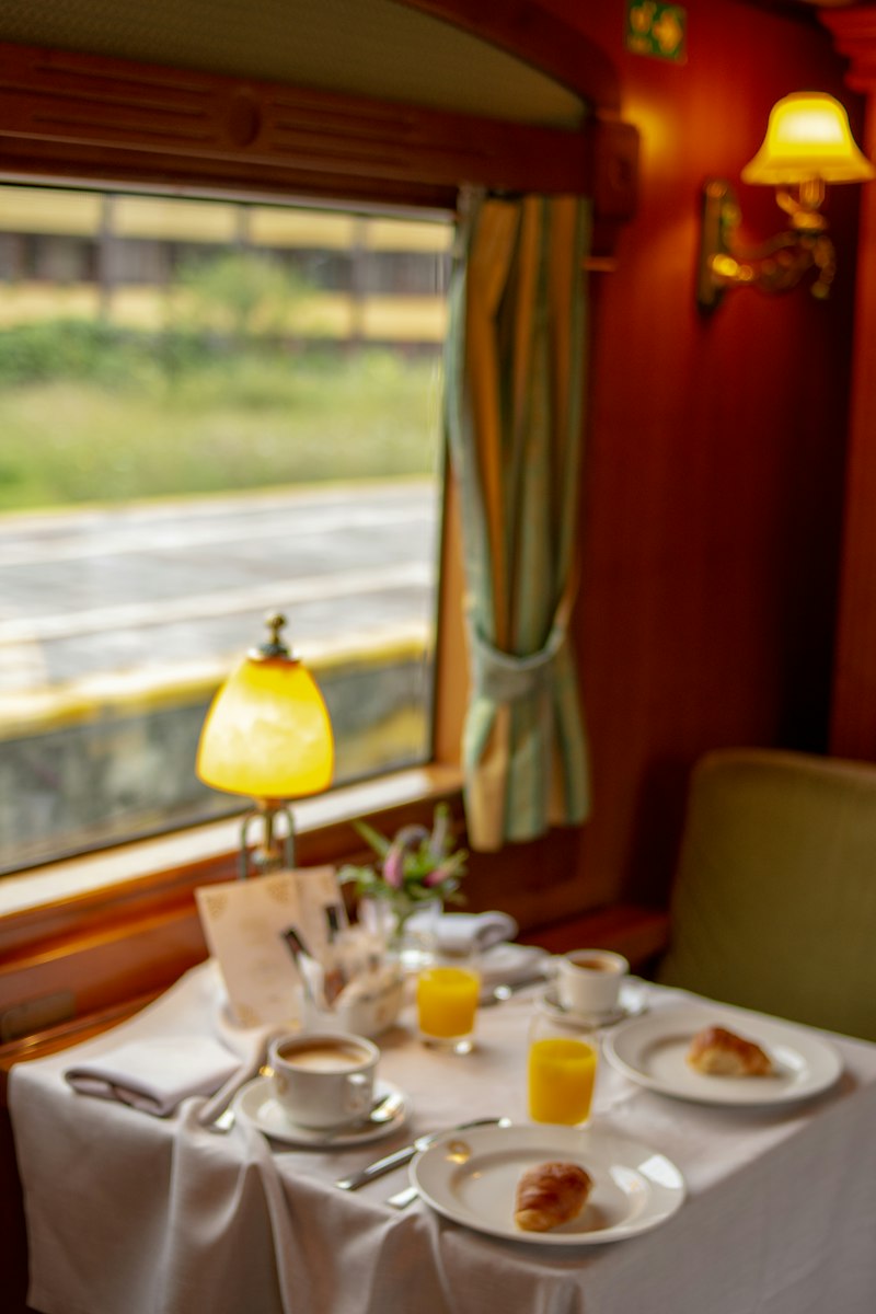 Breakfast laid out on white linen beside the window of a vintage sleeper carriage
