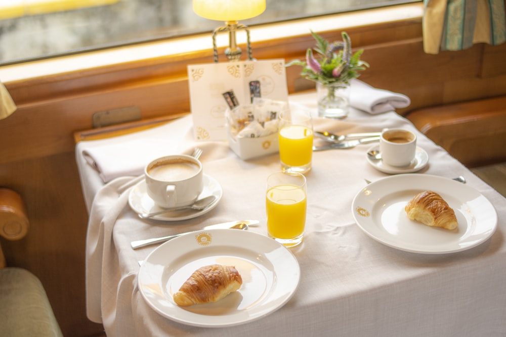 a white table topped with plates of food and cups of coffee