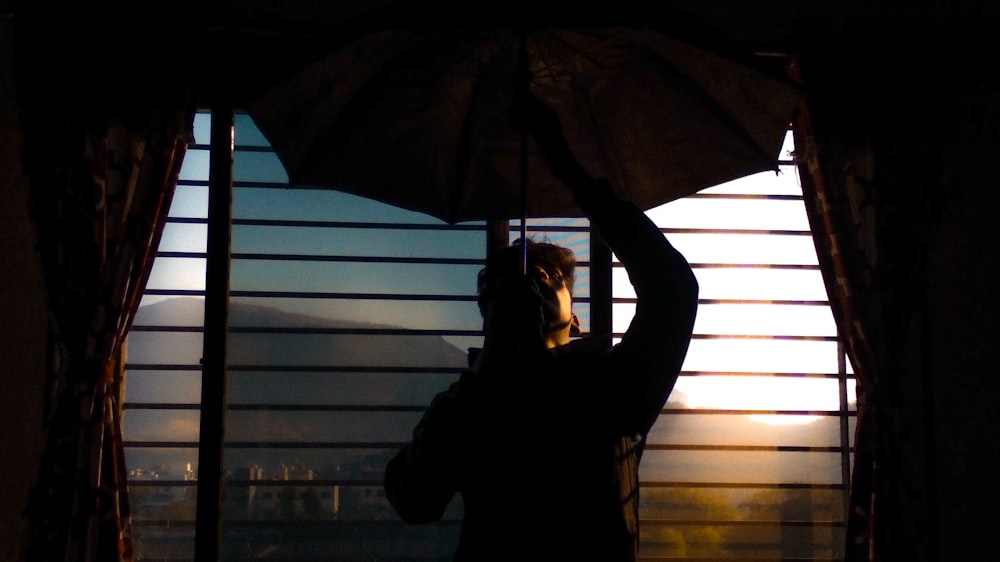 a person holding an umbrella in front of a window