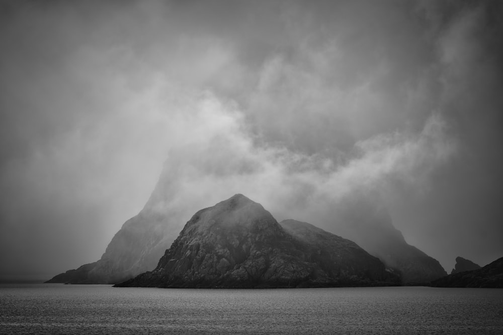 a black and white photo of a mountain in the middle of the ocean