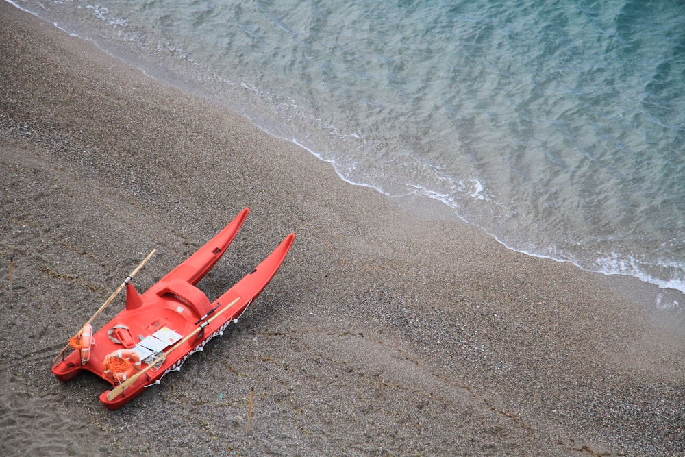 a red boat on a beach near the ocean