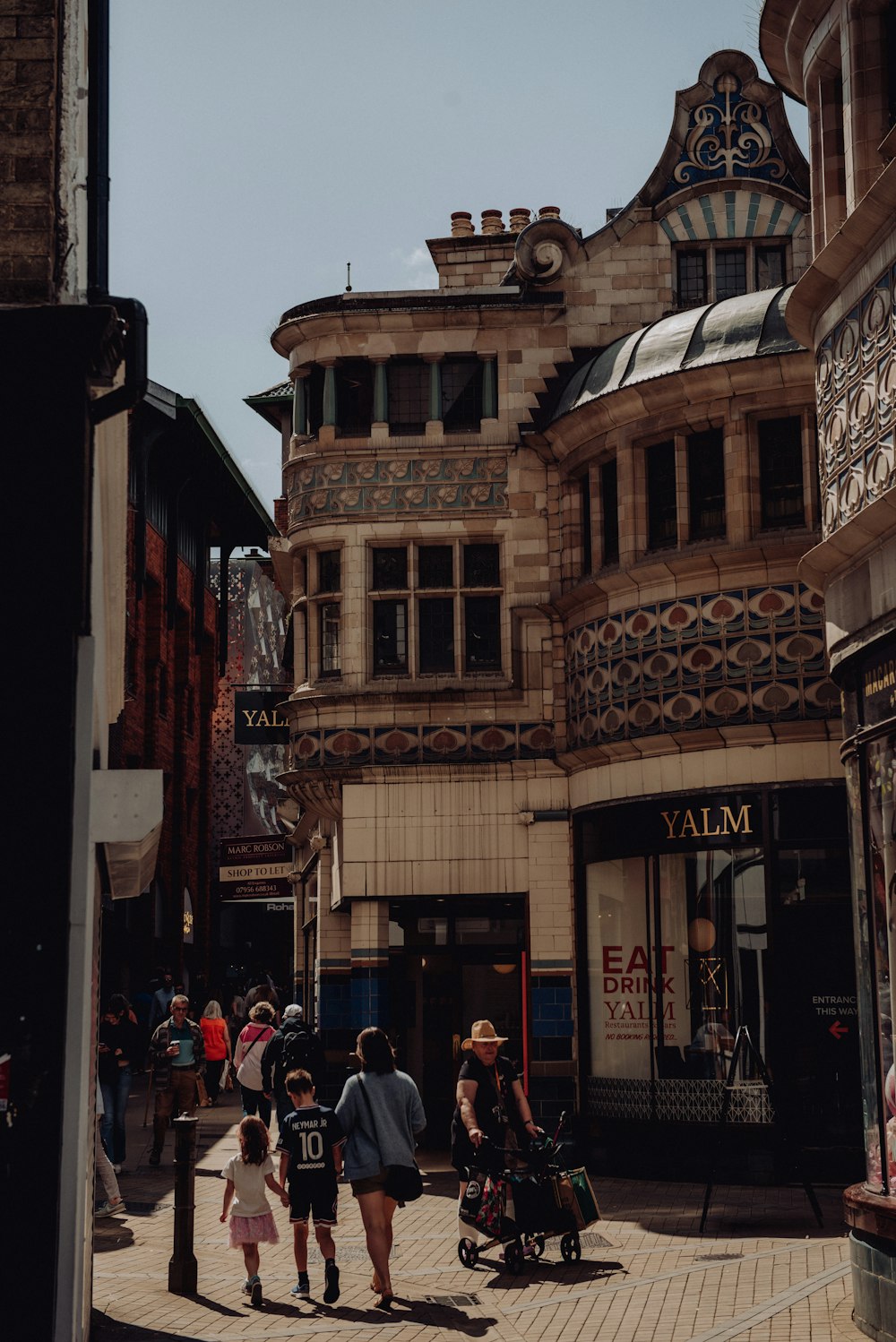 a group of people walking down a street next to tall buildings