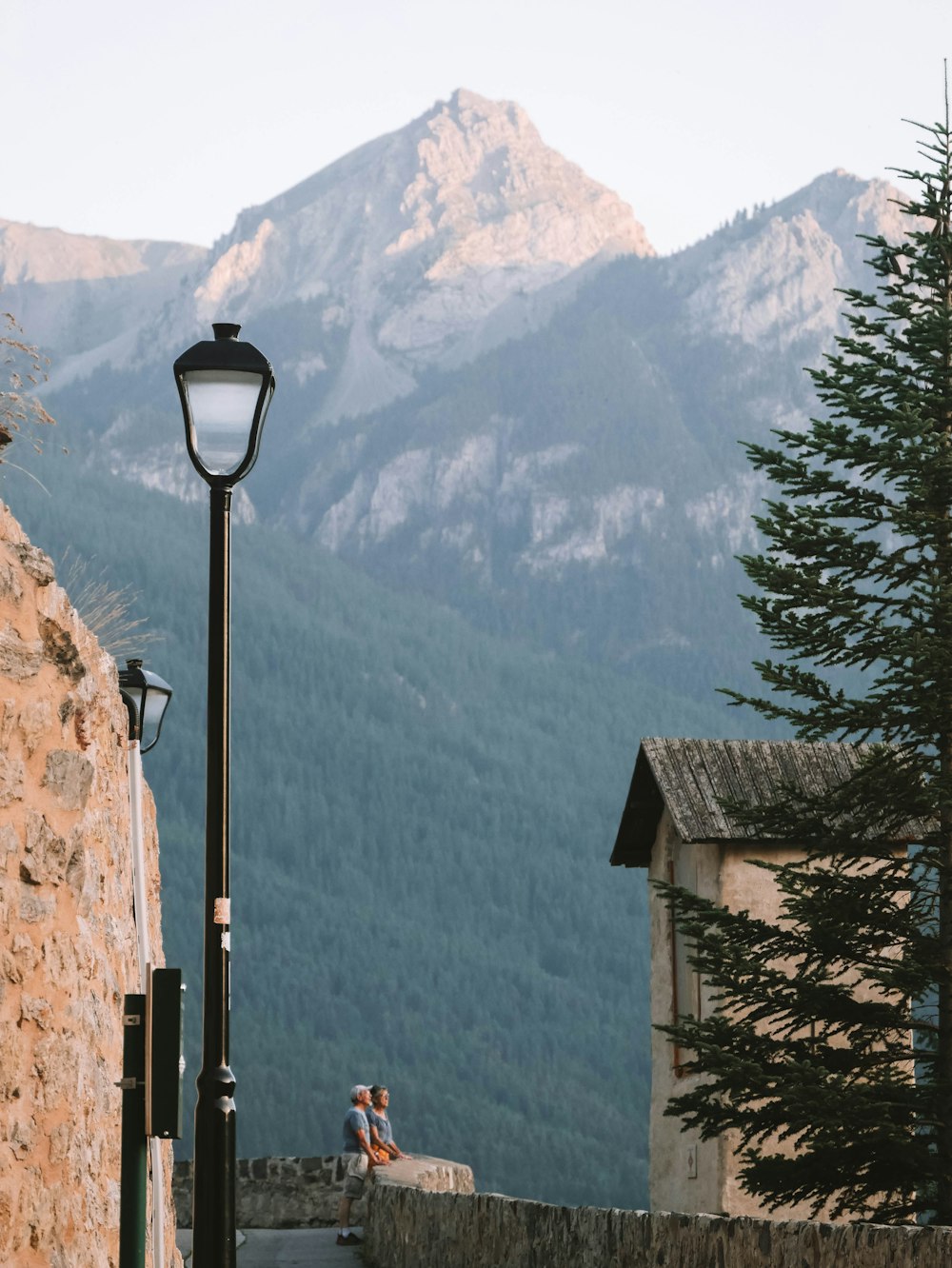 a couple sitting on a stone wall next to a street light