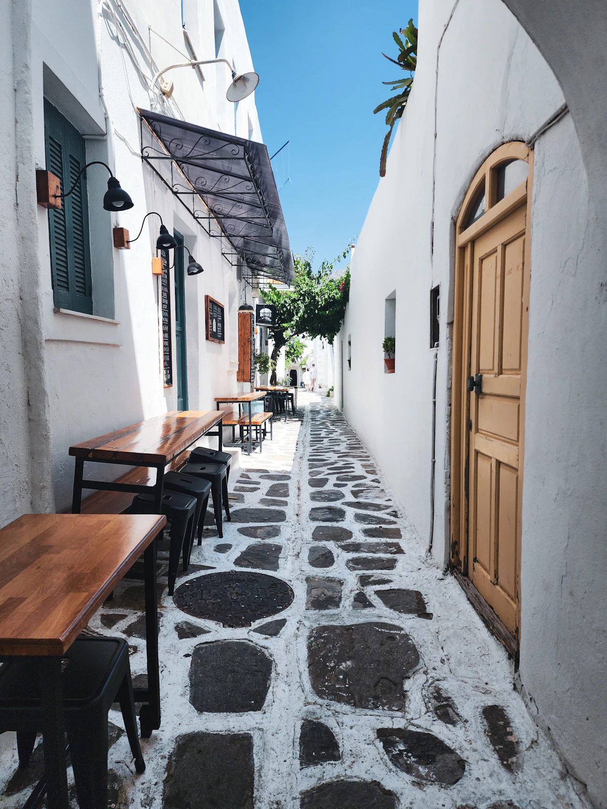 Narrow whitewashed alley in Naoussa old town with tables outside
