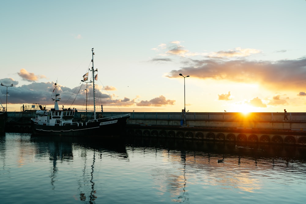 a boat is docked at a pier at sunset