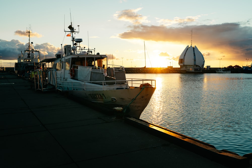 a boat docked at a pier with the sun setting in the background