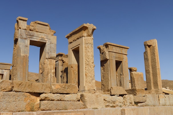 Tourists exploring ancient ruins under a clear blue sky.