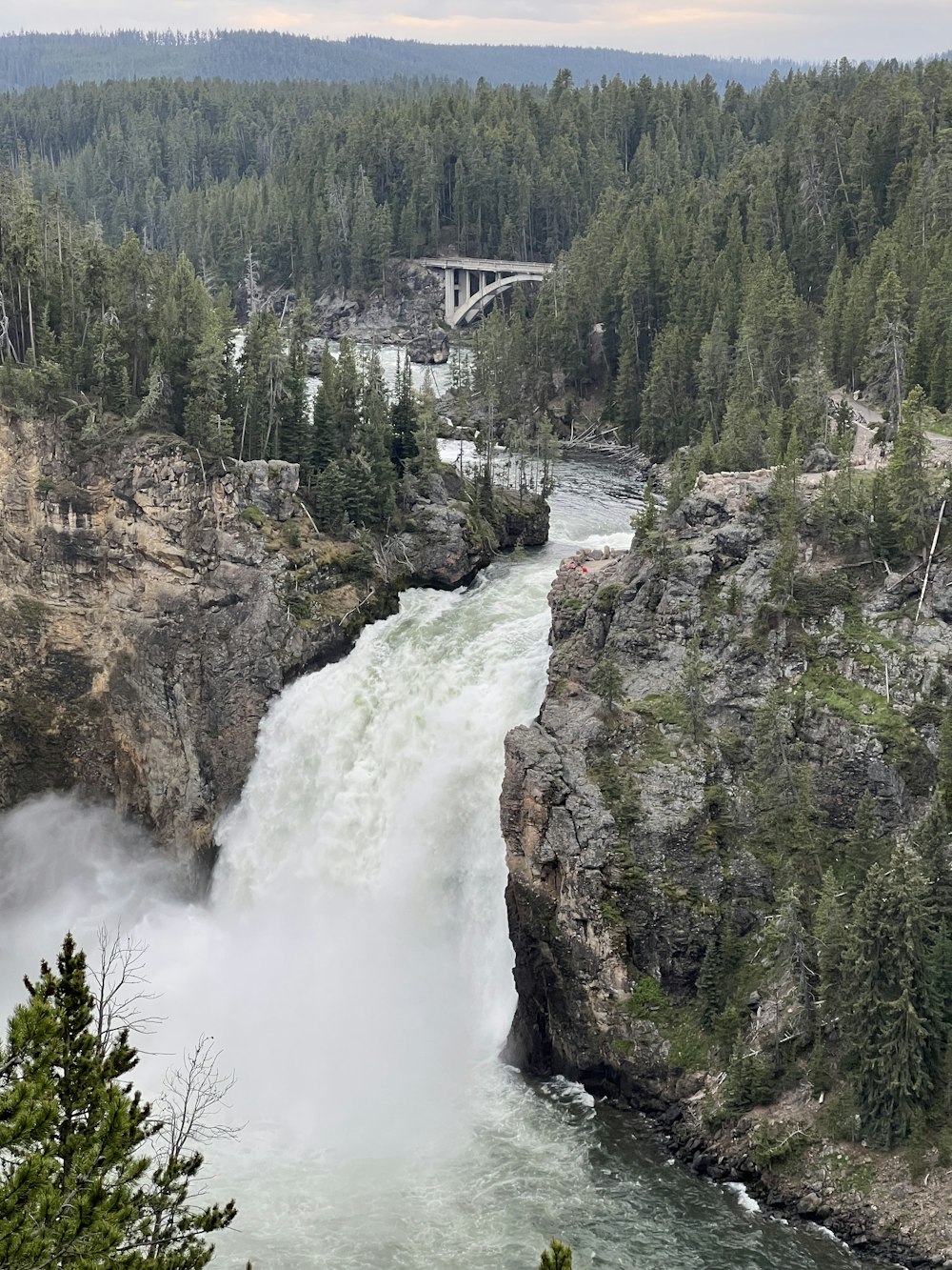 a large waterfall with a bridge in the background