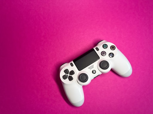 A colorful gaming controller with playful icons floating around it on a bright background.