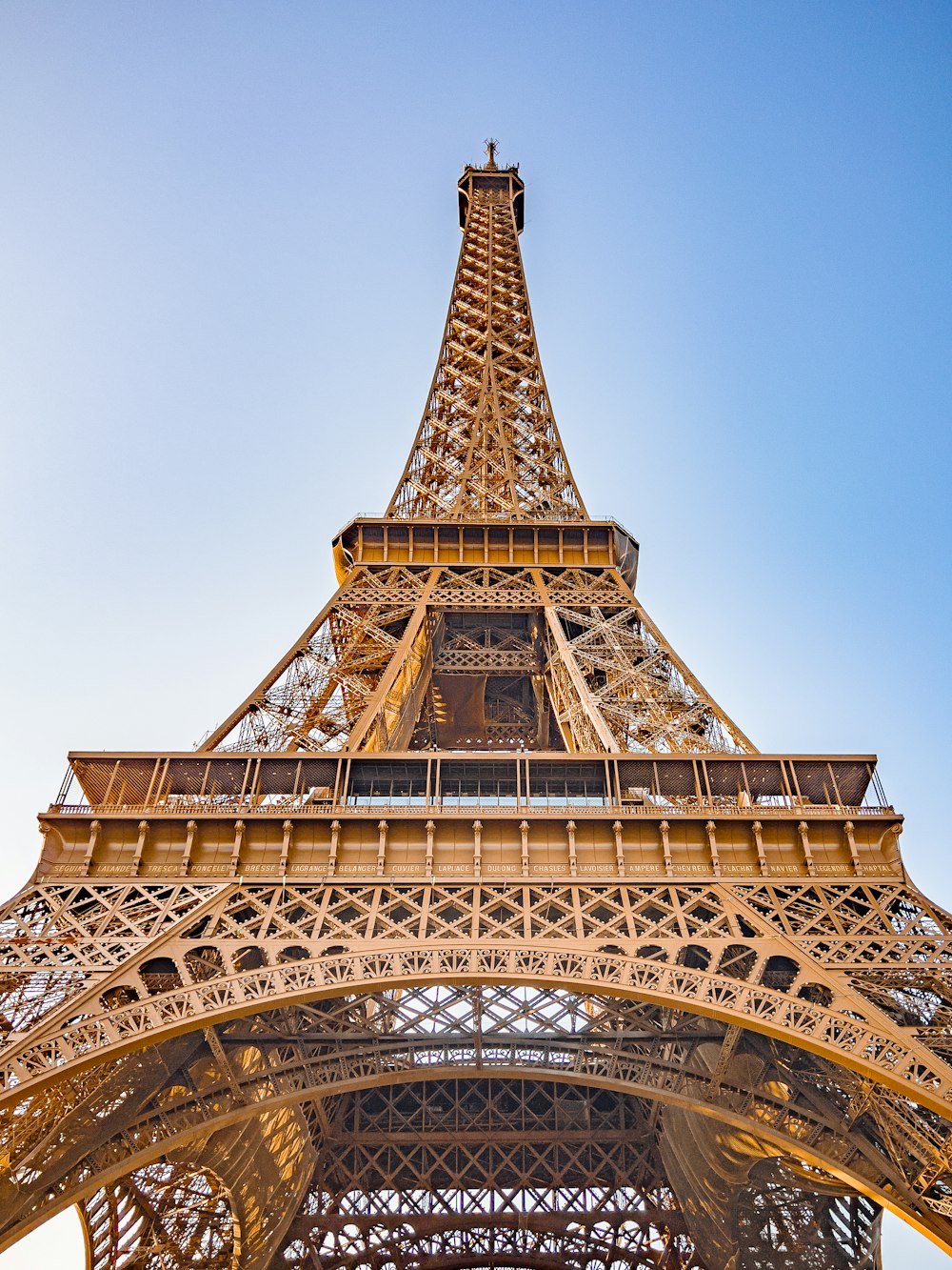 the top of the eiffel tower against a blue sky