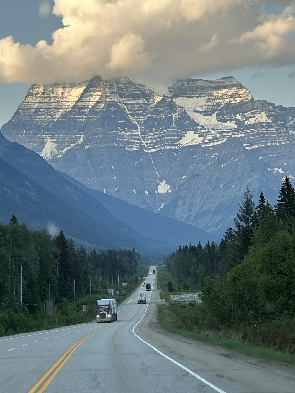a truck driving down a road with a mountain in the background
