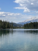Serene mountain lake reflecting the early morning sky and pine trees.