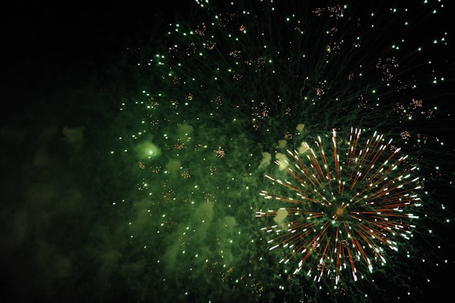 The subtle green bunny skull logo glowing faintly behind a dazzling fireworks display.