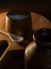 Hands holding coarse sea salt over a rustic wooden table.