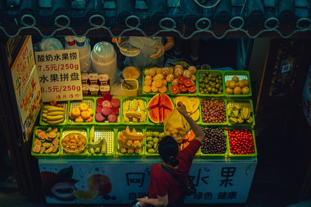 a person standing in front of a fruit stand