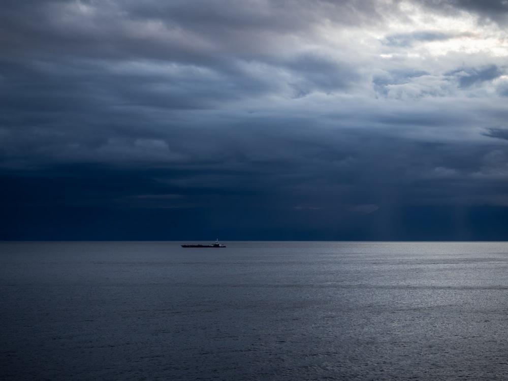 a boat in the ocean under a cloudy sky