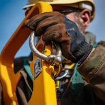 Close-up of sturdy safety gloves gripping a heavy tool against a blurred construction background.
