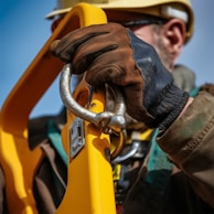 a man in a hard hat and safety gear holding a yellow safety gate