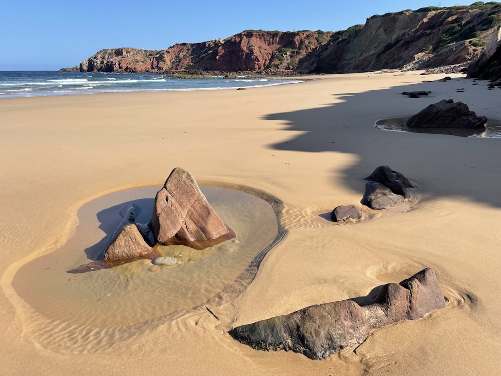 a sandy beach with rocks in the sand