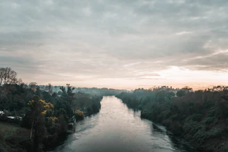 A serene river flowing gently through lush green hills under a soft sunset sky.