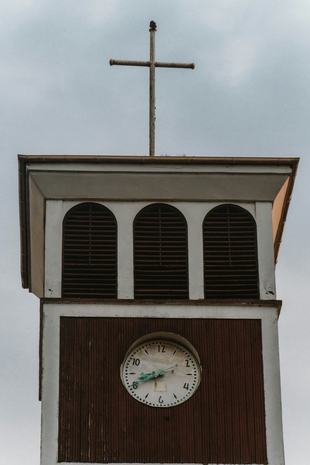 a clock tower with a cross on top of it