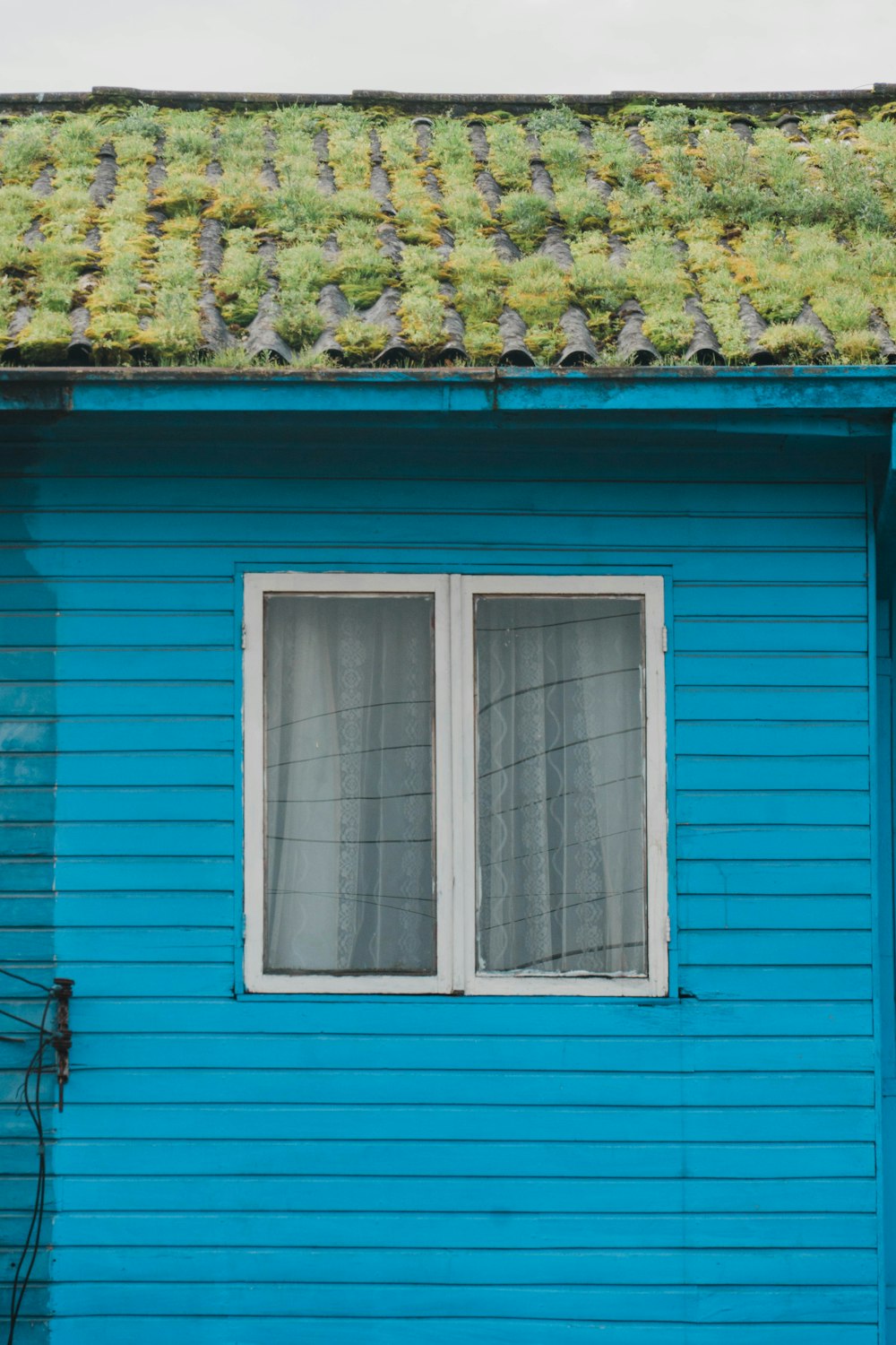 a blue house with a green roof and two windows