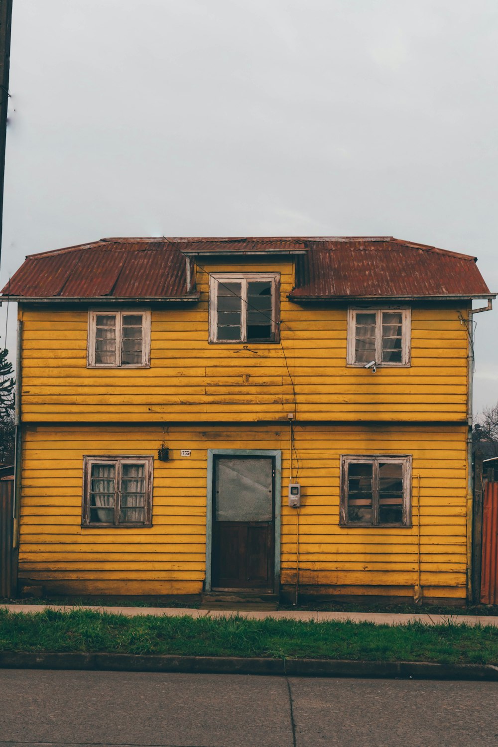 an old yellow house with a rusty roof