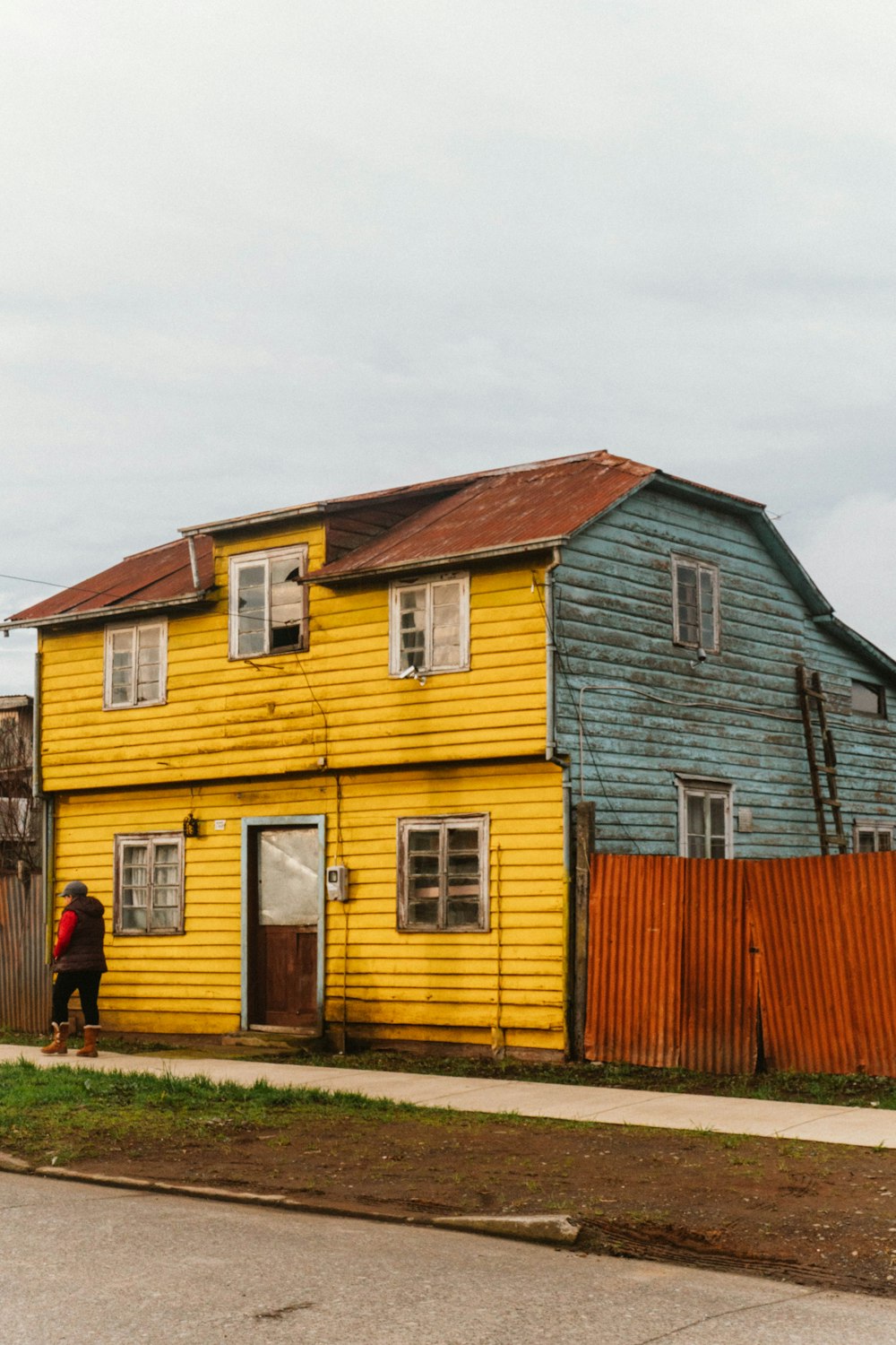 a person walking past a yellow and blue house