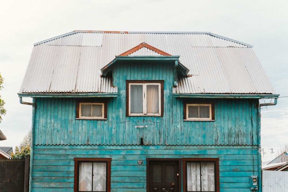 a blue wooden house with a metal roof