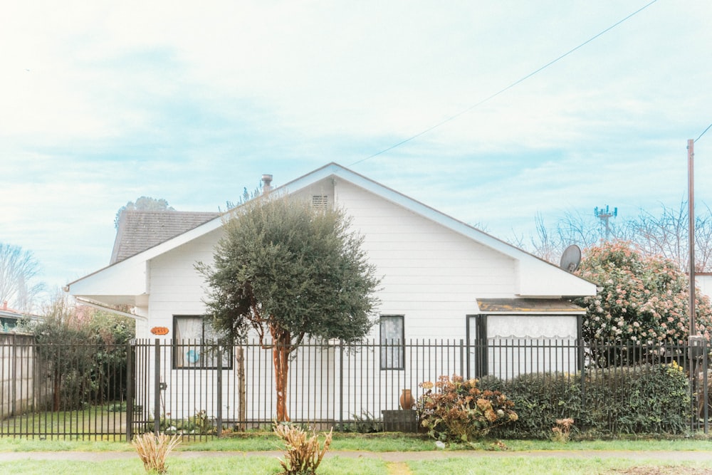 Una casa bianca con una recinzione nera di fronte