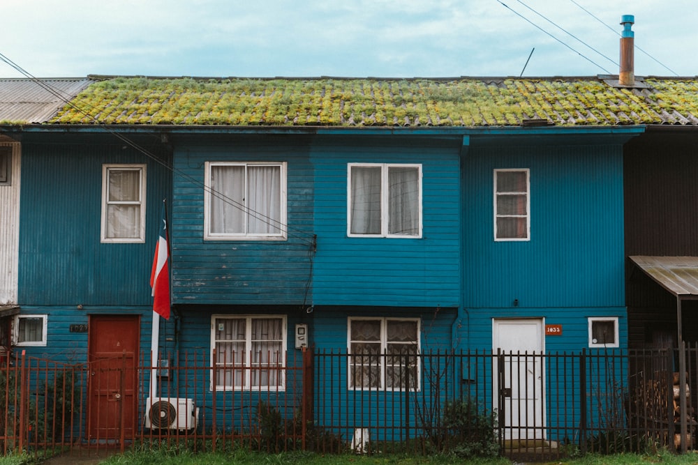 a blue building with a green roof and a red door